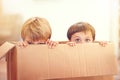 Children, box and eyes of siblings playing in a house with fun, bonding and hide and seek games. Cardboard, learning and Royalty Free Stock Photo