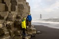 Children, boy brothers, posing on the rock of black sand beach of Reynisfjara and the mount Reynisfjall in Iceland on a cold Royalty Free Stock Photo