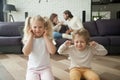 Children boy and girl covering ears, parents arguing at backgrou