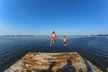 The children, a boy and a girl jumping from a wooden pier in the water Royalty Free Stock Photo