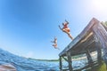 The children, a boy and a girl jumping from a wooden pier in the water.Toning Royalty Free Stock Photo