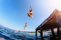 The children, a boy and a girl jumping from a wooden pier in the water.Toning Royalty Free Stock Photo