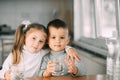 Children boy and girl in the kitchen drinking water from glasses, hugging and smiling Royalty Free Stock Photo