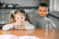 Children boy and girl in the kitchen drinking water from glasses Royalty Free Stock Photo