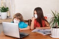 Children boy and girl in medical masks on distance education, watching online webinar while quarantine at home. Homeschooling and Royalty Free Stock Photo