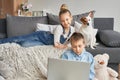 Children boy and girl playing on tabletand watching videos on laptop. Home schooler kids with dog, home schooling, home education