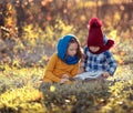 Children boy and girl read a book together while sitting on the grass in nature in the park Royalty Free Stock Photo