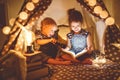 Children boy and girl reading book with flashlight in tent Royalty Free Stock Photo