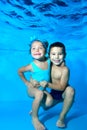 Children, a boy and a girl, smile and pose under the water in the pool on a blue background. Portrait. Close-up Royalty Free Stock Photo