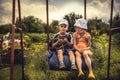 Children boy and girl swinging together in summer day on backyard in countryside concept happy chilhood