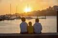 Children, boys, brothers, enjoying sunset over river with their pet maltese dog and mom, boats, sun, river Royalty Free Stock Photo