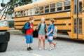 Children boys and girl kids students standing and talking near yellow school bus. Friends schoolmates classmates meeting after