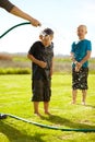 Children, boys and hose pipe with splash, water fun and playing outdoor in backyard or garden for sunshine. Kids Royalty Free Stock Photo