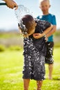 Children, boys and hose pipe with water fun, splash and playing outdoor in backyard or garden for sunshine. Kids Royalty Free Stock Photo