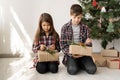Children brother and sister with Christmas gifts are sitting on the floor of the room near the tree. Boy and girl look Royalty Free Stock Photo