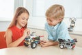 Robotics. Brother and sister having class sitting making robots cheerful Royalty Free Stock Photo
