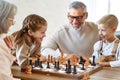 Children brother and sister playing chess while sitting in living room with senior grandparents Royalty Free Stock Photo