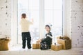 Children brother and sister of preschool age sit by window on a sunny Christmas day and play with gifts boxes wrapped in paper.The Royalty Free Stock Photo