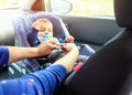 Children car chair. baby car seat for safety. Protection in the car. woman is fastening security belt to child, who is sitting in Royalty Free Stock Photo