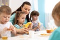 Children and carer together eat fruits in kindergarten or daycare