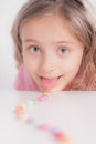Children and chocolate. Joyful girl with sweets.A cheerful girl plays and eats chocolate multi-colored round candies on a light Royalty Free Stock Photo