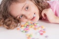 Children and chocolate. Joyful girl with sweets.A cheerful girl plays and eats chocolate multi-colored round candies on a light Royalty Free Stock Photo