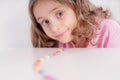 Children and chocolate. Joyful girl with sweets.A cheerful girl plays and eats chocolate multi-colored round candies on a light Royalty Free Stock Photo