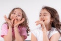 Two cheerful girls eat chocolate on a light background. Children and chocolate