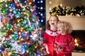 Children at Christmas tree. Kids at fireplace on Xmas eve Royalty Free Stock Photo