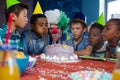 children with clown blowing candles on cake Royalty Free Stock Photo
