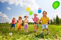 Children with colorful balloons running in field