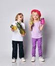 Children, colorful casual clothes. Laughing, holding yellow and pink cocktail bottles, apple, pineapple. Posing isolated on white