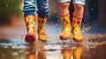 Children with colorful gum boots splashing water in muddy puddles.