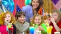 Children in colorful hats celebrating birthday with mother and fiends.