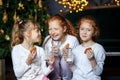 Children communicate near the Christmas tree. The sisters drink milk and laugh