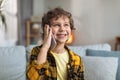 Close up portrait of happy little boy talking with friends via smartphone, resting at home interior, free space Royalty Free Stock Photo