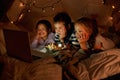 Children, computer and watch in tent at night with movies, film or cartoons for holiday adventure or vacation. Young boy