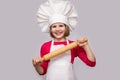 Children cook. Happy little girl in chef uniform holds rolling pin isolated on white background Royalty Free Stock Photo