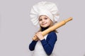 Children cook. Happy little girl in chef uniform holds rolling pin isolated on white background Royalty Free Stock Photo