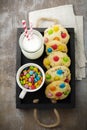 Children cookies with colorful chocolate sweets in sugar glaze on a brown wooden background. Selective focus. Top view. Place