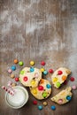 Children cookies with colorful chocolate sweets in sugar glaze on a brown wooden background. Selective focus. Top view. Place