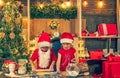 Children are cooking Christmas cookies in cozy home kitchen. Two chldren in santa hats and aprons preparing christmas Royalty Free Stock Photo