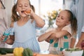 Children, cooking and a girl eating a carrot in the kitchen while preparing a healthy meal with her family. Kids, food Royalty Free Stock Photo