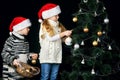 Children decorate the Christmas tree in the room. Royalty Free Stock Photo