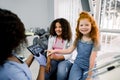 Children at dentist`s office. Two multiethnic teen girls, sitting in dentistry chair, looking at camera and pointing on