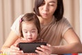 Children with down syndrome and gadgets, mom and girl with a tablet, online communication with family and friends