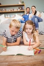 Children drawing on book while parents looking at them Royalty Free Stock Photo