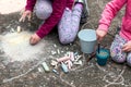 Children drawing with chalk on the concrete sitting on the ground. Art therapy, CBT, simple creativity excercises. Two girls
