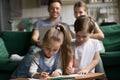 Children drawing with colored pencils while parents using laptop Royalty Free Stock Photo