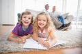 Children drawing on papers while parents sitting on sofa Royalty Free Stock Photo